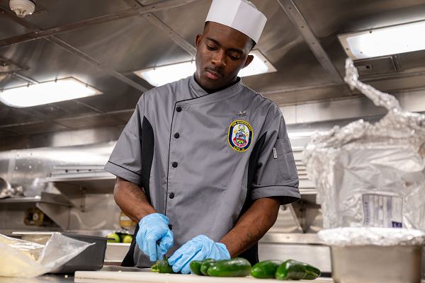 PACIFIC OCEAN (Feb. 13, 2024) Culinary Specialist 2nd Class Nathan Bradley, a native of New York, cuts jalapenos in the galley aboard the San Antonio-class amphibious transport dock ship USS Somerset (LPD 25) while underway in the Pacific Ocean, Feb. 13, 2024. Somerset is currently underway conducting routine operations in U.S. 7th Fleet with elements of the 15th Marine Expeditionary Unit. U.S. 7th Fleet is the U.S. Navy's largest forward-deployed numbered fleet, and routinely interacts and operates with allies and partners in preserving a free and open Indo-Pacific region. (U.S. Navy photo by Mass Communication Specialist 2nd Class Evan Diaz)